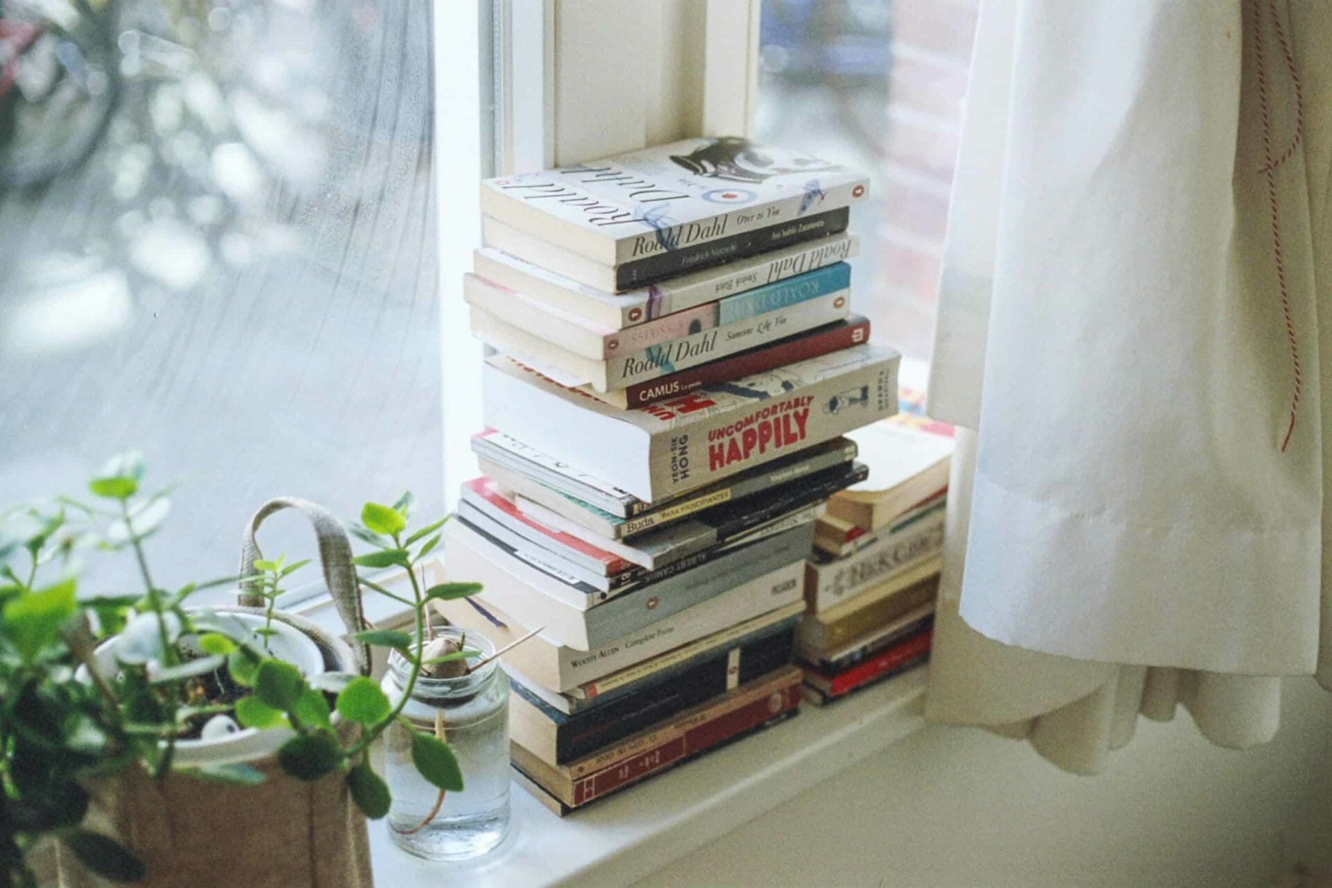 a pile of books on a window sill