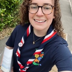 Georgia with brown curly hair, smiling as she takes a selfie in her Scout uniform!