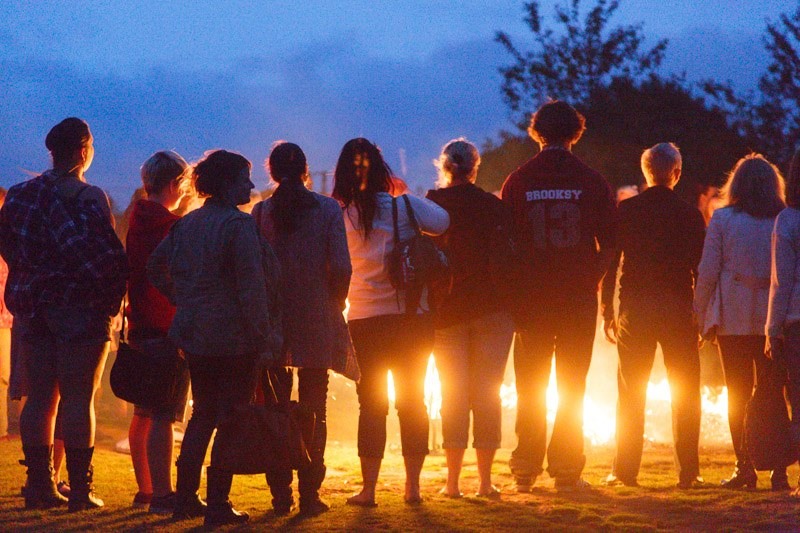 A group of participants look at the firelane. We are behind them and the flames of the fire is glowing through their legs.