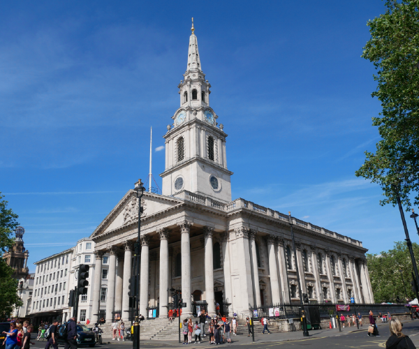 An image of St Martin-in-the-fields Church, London. A tall white spire and a colonnade of columns.