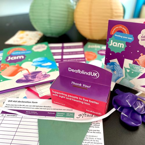 The contents of the Cream Tea Jamboree host kit are arranged attractively on a table, including guide booklet, collectin box, game posters, balloons and more.