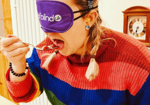 A woman eating a meal while blindfolded