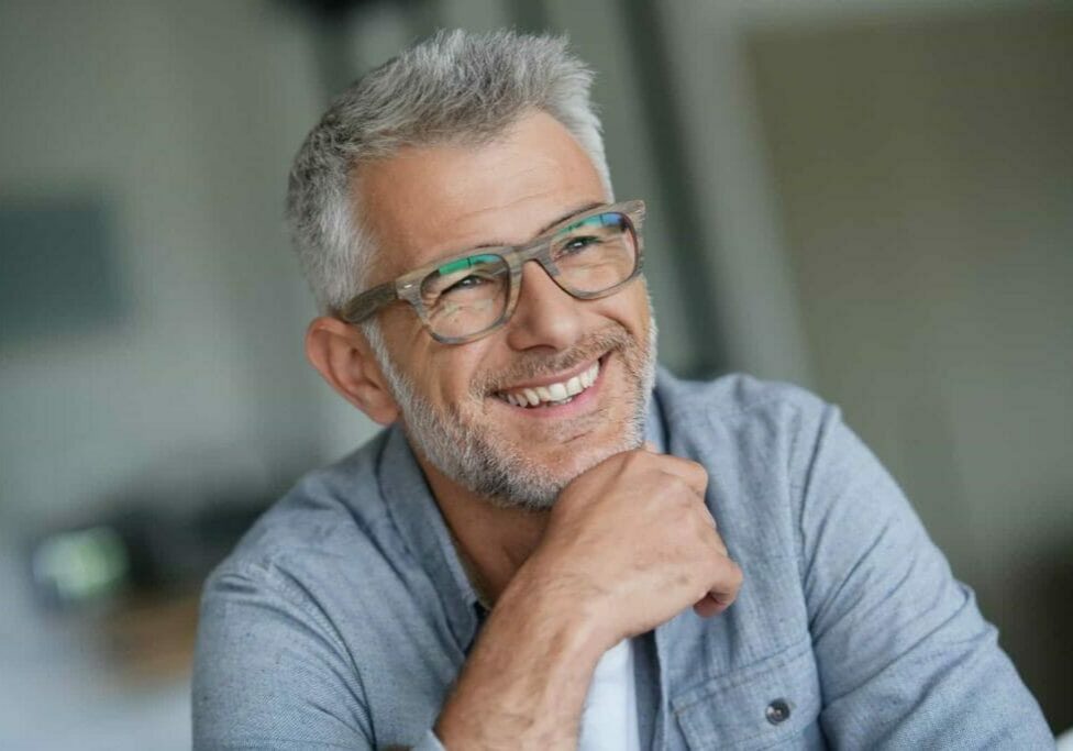 A middle aged man wearing glasses, smiling